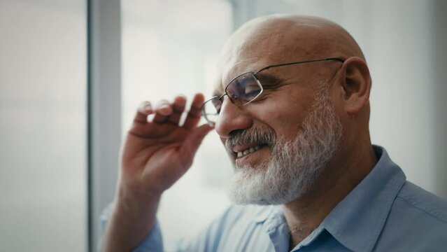 Happy middle-aged man looking out the window, good day, nice mood, success