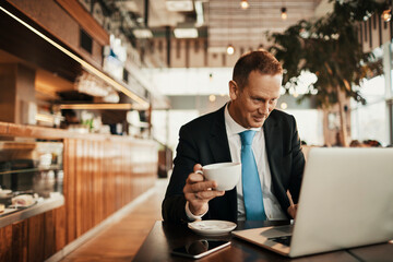 Mature businessman holding a cup of coffee in a cafe