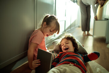 Young children sharing a moment with a tablet in a cozy living room