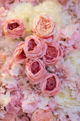 Floral background texture for ceremony or photo shoot. Artificial flowers in pastel colors on the wall. Selective focus.