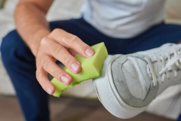 Cleaning suede sneakers. A worker in a shoe workshop cleans a pile of shoes