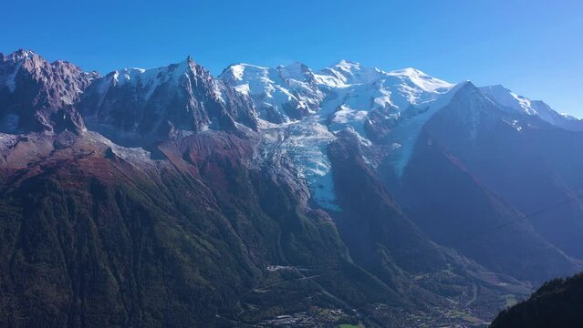 Mont Blanc and Aiguille du Midi Mountains on Sunny Day. French Alps, France. Aerial View. Drone Flies Backwards over a Rocky Mountain at Low Level