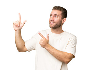 Young handsome caucasian man isolated on green chroma background pointing with the index finger a great idea
