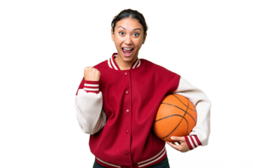 Young Uruguayan woman playing basketball over isolated wall  over isolated chroma key background celebrating a victory in winner position