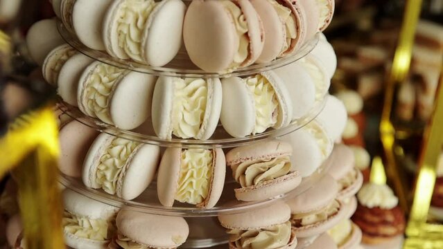 Fresh pastel coloured macaroons or macarons baked from almond flour and smeared with cream stand in pyramid shape on gourmet buffet, candy bar. Expensive cookies. French confectionery