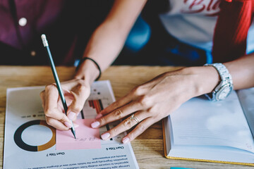 female hands making notes on paper stick during collaboration with partner employee
