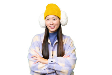 Young Asian woman wearing winter muffs over isolated chroma key background keeping the arms crossed in frontal position