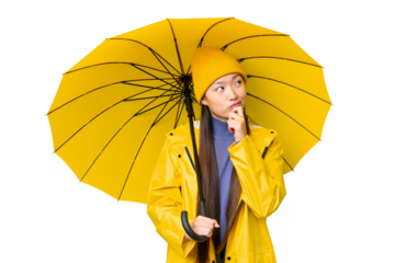 Young Asian woman with rainproof coat and umbrella over isolated chroma key background and looking up