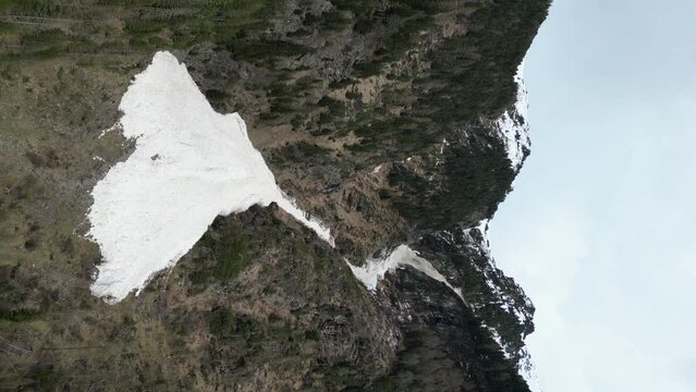 Aerial view of an avalanche in the mountains. Vertical video of natural dangerous processes of snow climbing from mountain slopes. High quality 4k footage