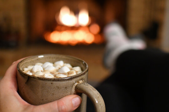 Relaxing by the fireplace fire in winter with mug of hot cocoa chocolate while wearing fuzzy socks