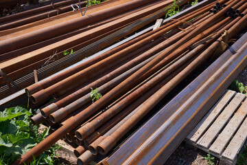 Scraps of rusty pipe of different sizes on rack in warehouse