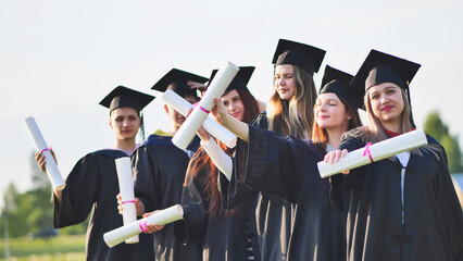 Cheerful graduates waving their diplomas on a sunny day.