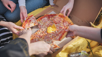 A group of hands reach for the pizza.