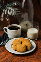 Crunchy cookies biscuits served in plate with black coffee and glass of milk isolated on table side view of american cafe baked food