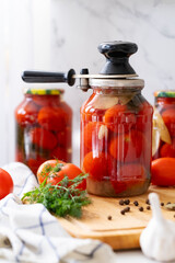 red tomatoes in canned jars stand on the kitchen table next to the jar there is a key for tightening the lid