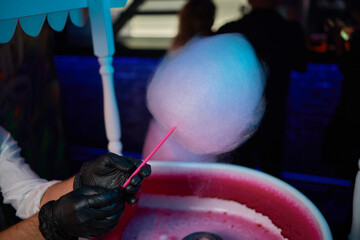 Hand rolling cotton candy in candy floss machine. Making candyfloss