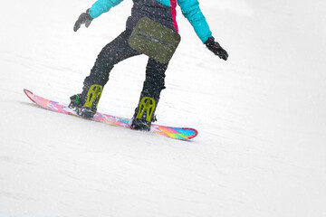 Fragment of a snowboarder on the snowy slope of a ski slope. Snowing. The background is white. Copy...