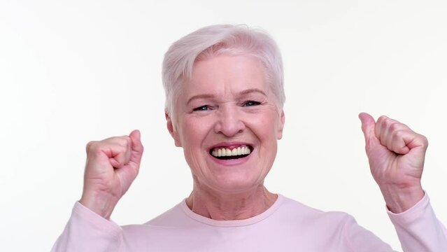Delighted Senior adult woman exclaims Yes with enthusiasm, eyes shining with happiness and expression brimming with joy. This image captures the genuine excitement and positivity of the moment.