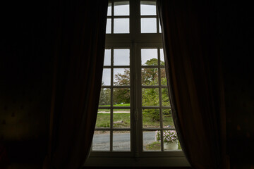 Window with curtains in the French Chateau overlooking the garden area