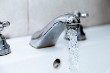Water faucet in the bathroom. Tap open with water running. Waste of drinking water.