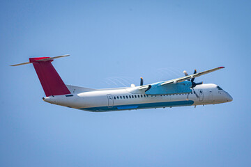 propeller airplane in flight in blue sky with visible wake vortices