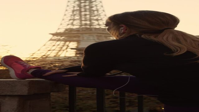 Slow motion of woman stretching leg while admiring Eiffel Tower  - vertical video / Paris, Ile de France, France