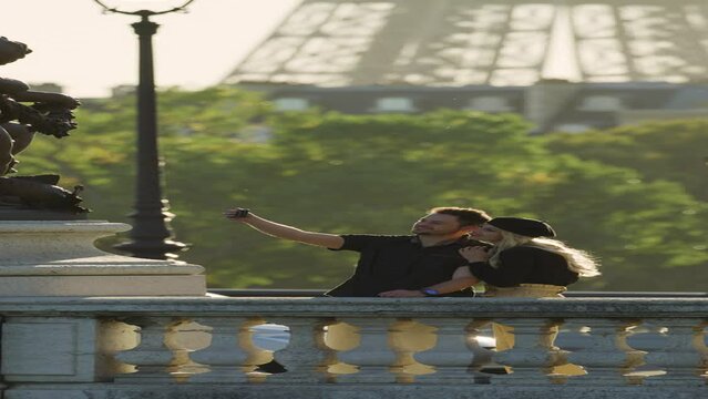 Happy couple posing for cell phone selfie near statues on Pont Alexandre  - vertical video / Paris, Ile de France, France
