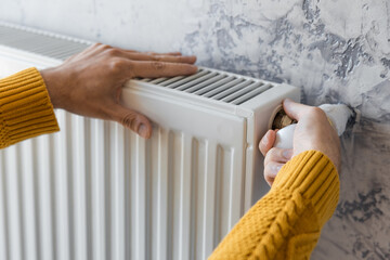 Man adjusting heating radiator or heater to install comfort temperature for energy efficiency and economy in winter. Concept of heating season