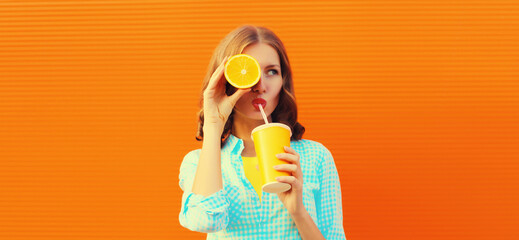 Summer portrait of happy young woman drinking fresh juice with slice of orange fruits and looking away on background - obrazy, fototapety, plakaty
