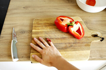 Female hand with blood. Woman wounded her little finger with knife while cutting red pepper on...