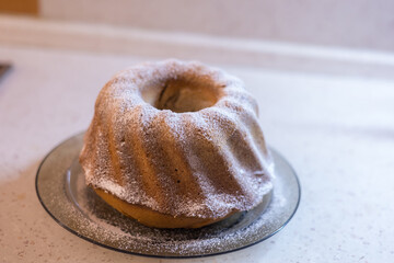Homemade cake on a plate. There is white sugar on the cake.