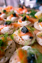 Smoked salmon, dill and caviar blinis with creme fraiche. Fine dining luxury New York-style brunch. Vertical food photography for Instagram stories. Perfect for the festive season, pair with champagne