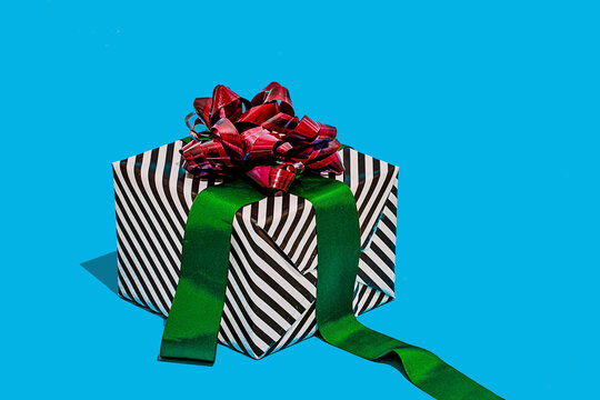 Striped gift box with red bow on blue surface