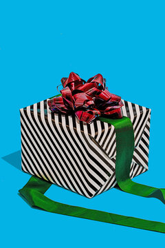 Striped gift box with red bow on blue surface