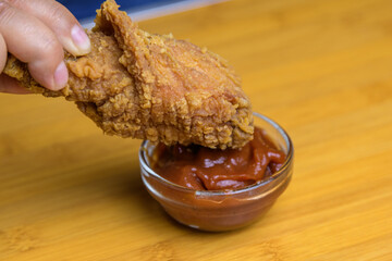 Hand holding a crispy fried chicken. Fast food