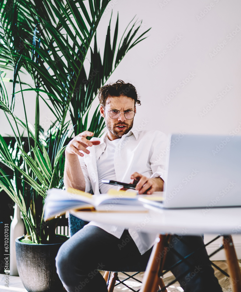Poster serious caucasian man using modern netbook for online job browse and downloading files
