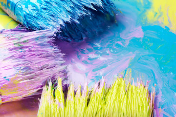 brushes with colored paints on a colored background