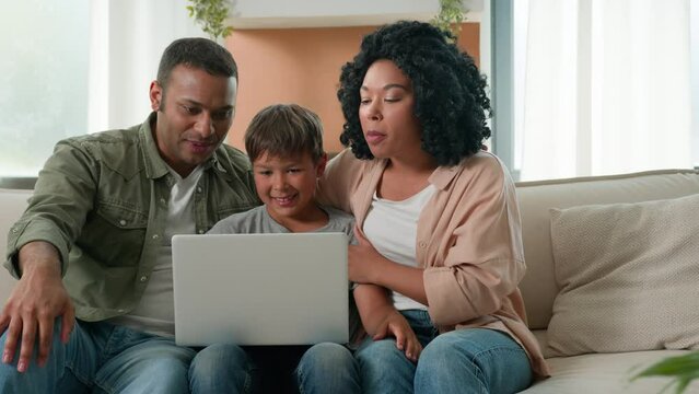 Multiracial family African American parents and Caucasian little boy son child talking use computer webcam video call happy mom dad teen kid communicate remote chatting online on laptop device at home