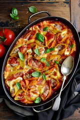 Stuffed pasta cannelloni with minced meat baked in  tomato sauce in a skillet. Top view with copy space.