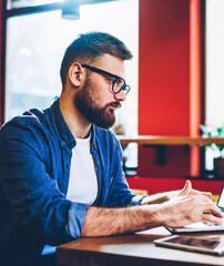 Fototapeta premium Skilled hipster guy working remotely with startup project on laptop device with copy space