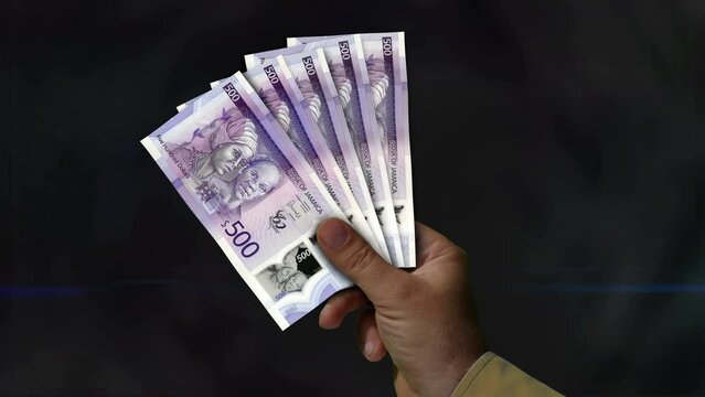 Jamaica Dollar money holding. Fan of banknotes in hand. JMD paper cash. Concept of income, success, business, tax, economy and finance.