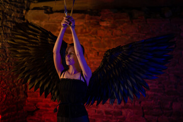 Black angel dot woman with her hands tied and tied to ceiling. BDSM, adult games