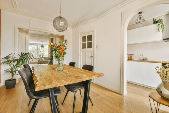Dining room with wooden table and black chairs - Powered by Adobe