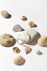 Jewelry made of gold and silver on a white background. Stylish compositions with hard shadows and natural stones. 