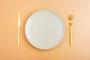 Empty plate with fork and knife on orange background. Diet concept. Top view, flat lay