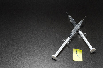 Post it with anti drugs concept. Stop drugs. Medical disposable syringes with a needle filled with liquid. Plastic syringe with medicine, drugs or vaccine, isolated on black background.