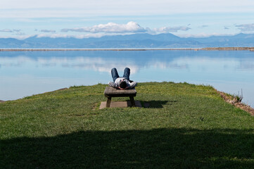 A person lies with their hands clasped behind their head, admiring the view out over the inlet at...