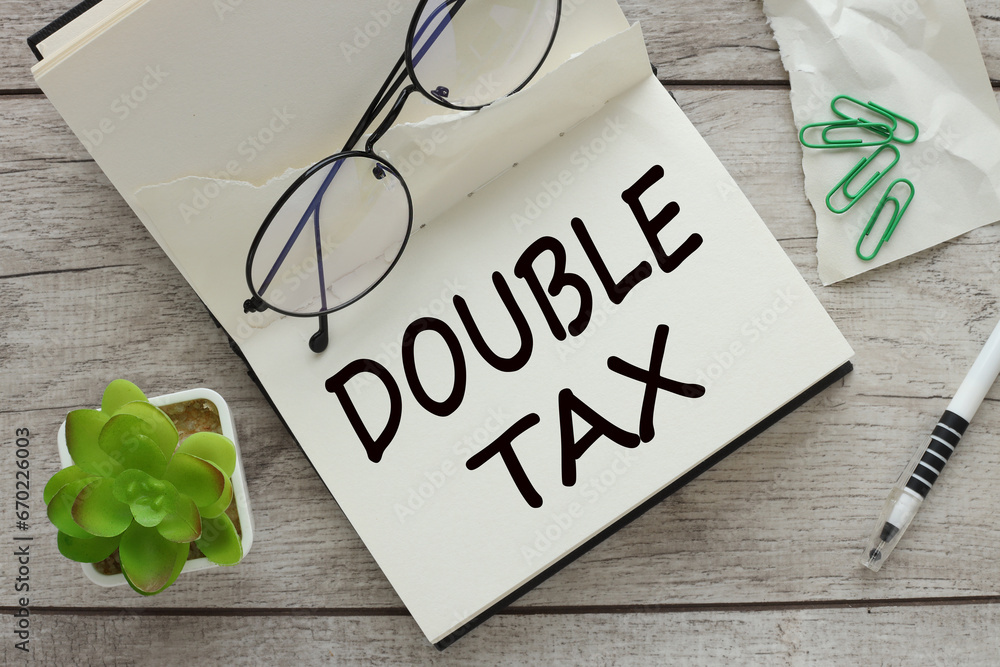 Poster double taxation text on a notepad page. glasses on the work table
