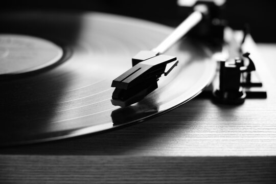 Classic vinyl record player closeup with contoured daylight from window in black and white photo.
