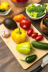 Different vegetables for cooking salad on cutting board with knife on table on kitchen. Healthy vegetarian vegan diet food concept